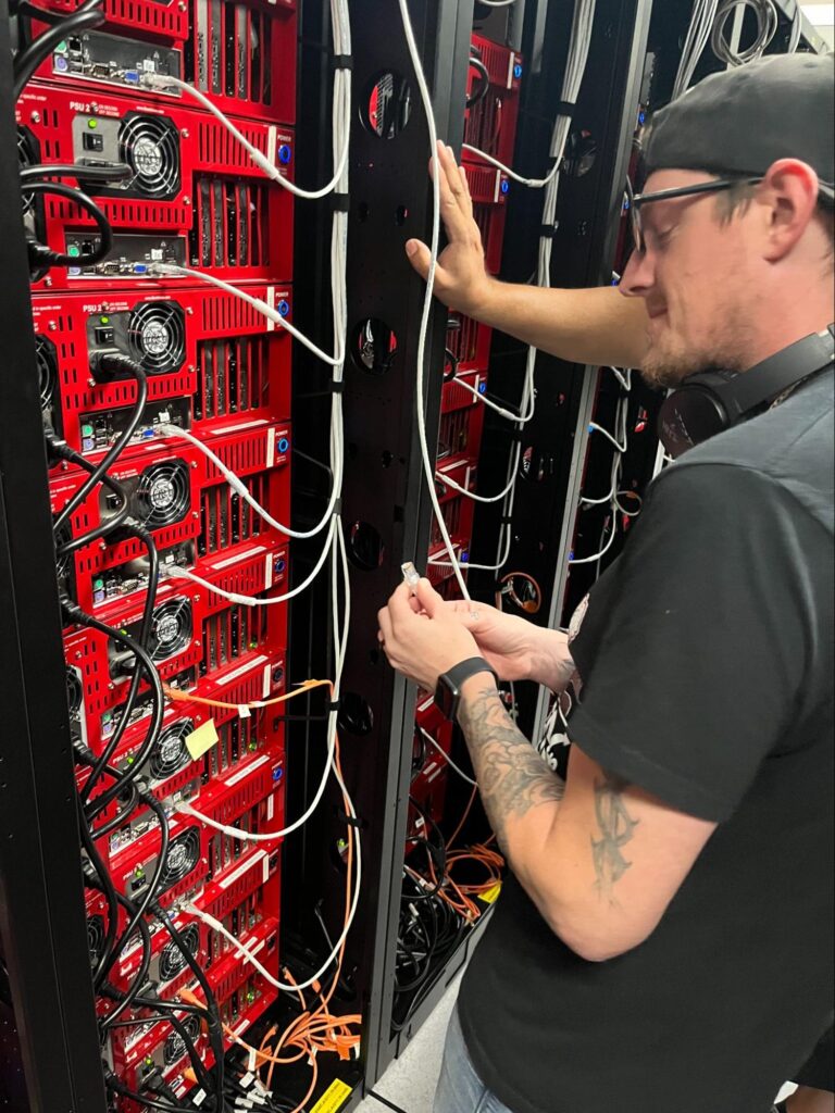 An image of a data center technician plugging network connections into servers. 